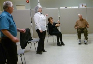 Photo of 4 seniors dancing moving their arms; 2 standing, 2 sitting